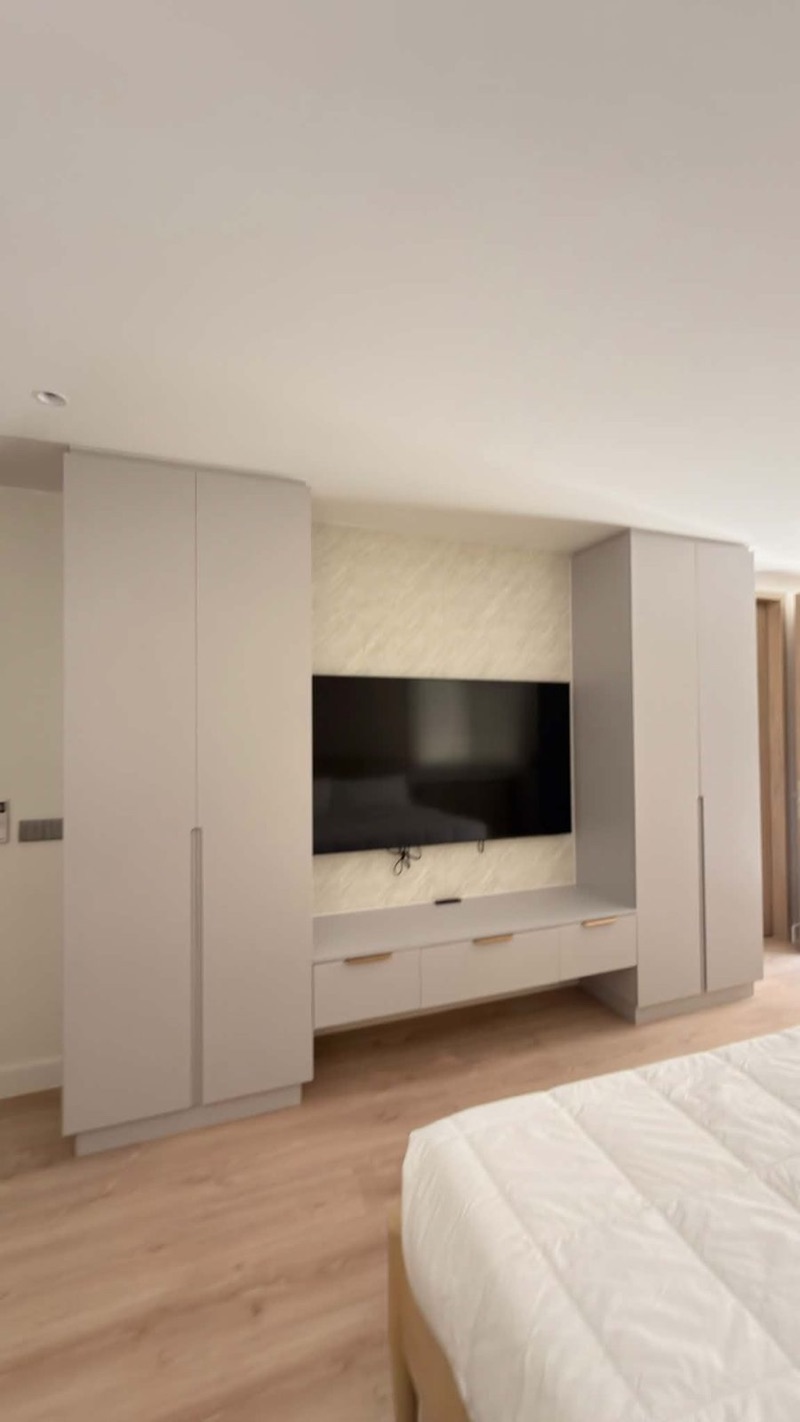 Bedroom wardrobes framing a quilted TV wall