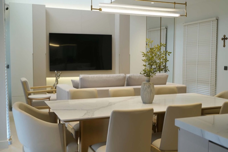 Dining area with a marble-top table in front of a white media wall