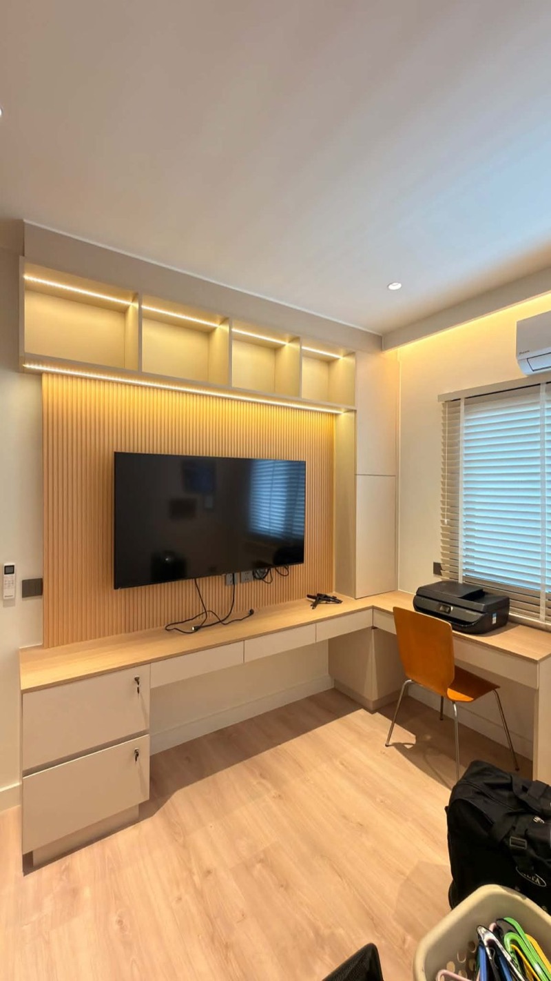 Desk wall with open oak shelves, drawers and a wall-mounted TV