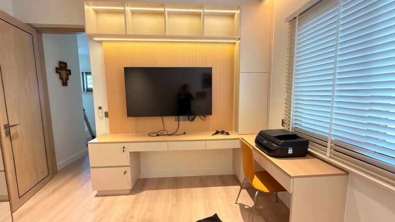 Study wall with an oak desk, drawers and lit overhead cubbies