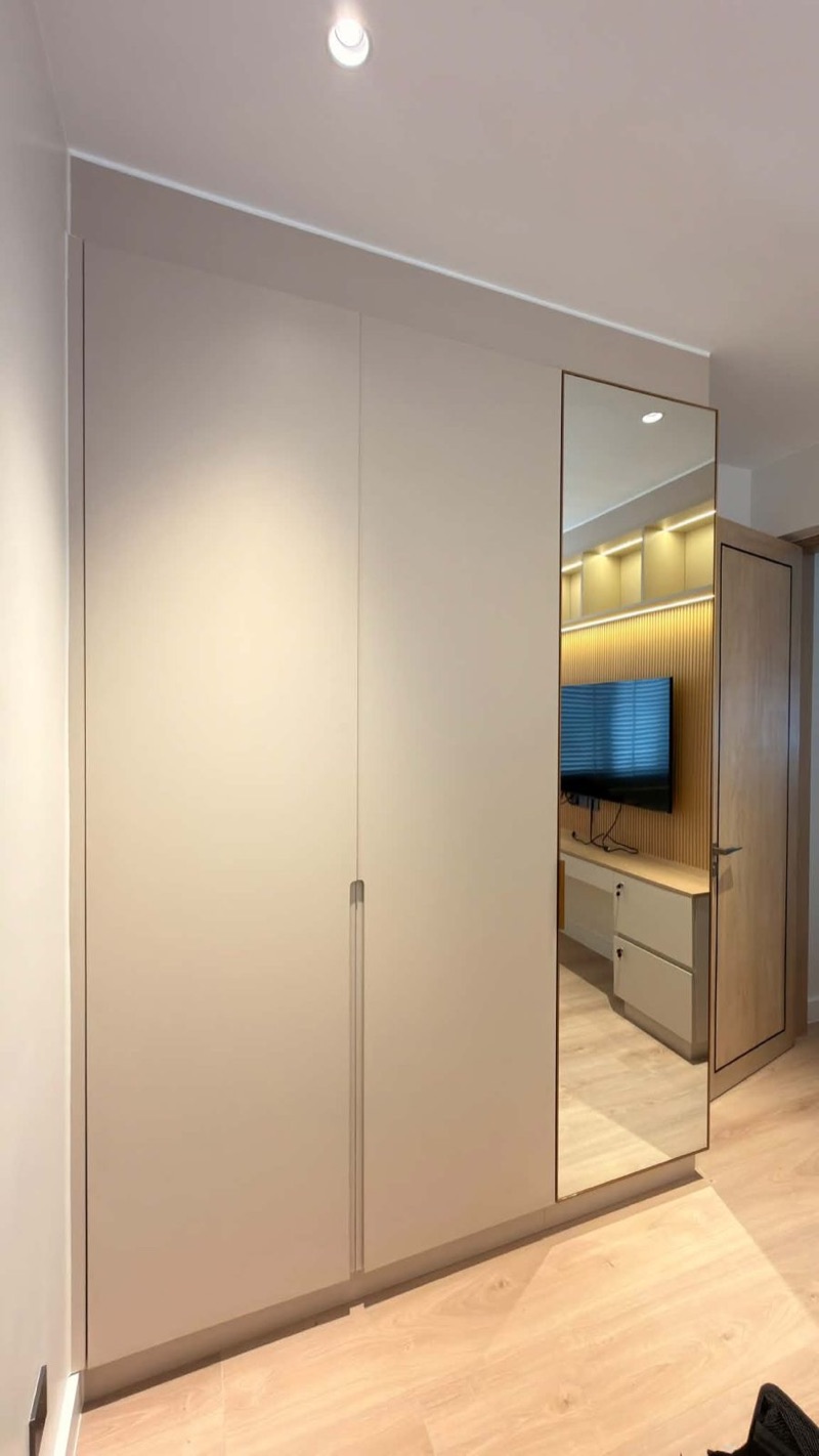 Full-height wardrobe with a mirrored door and a lit open shelf unit beyond