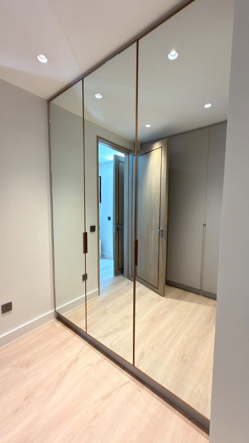Walk-through closet lined with mirrored wardrobe doors